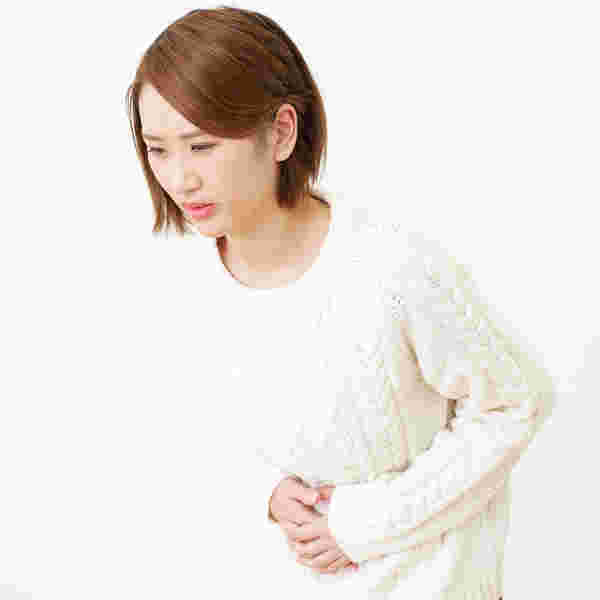 お腹を押さえながら前かがみになる女性