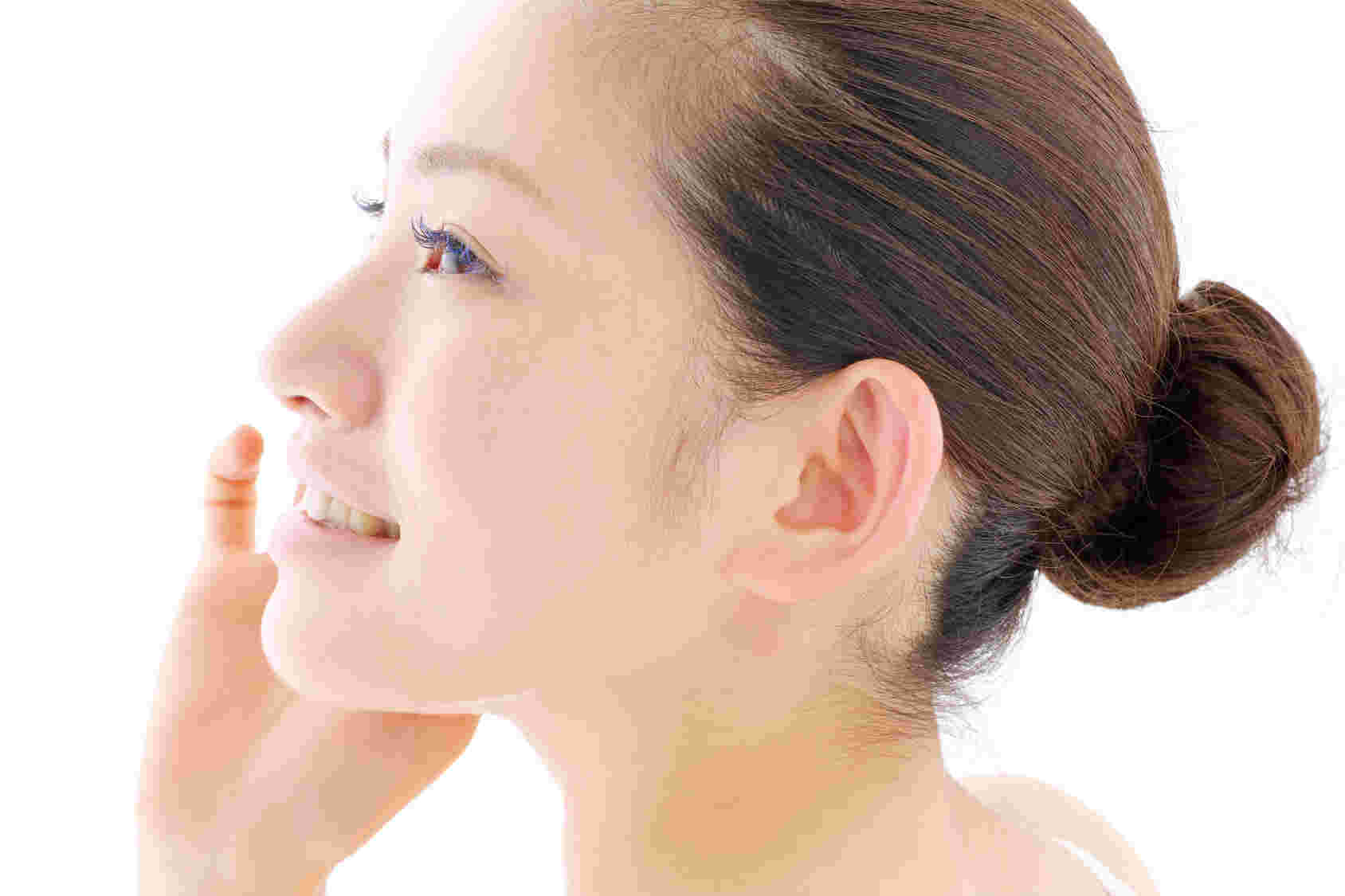 頬に手を当てて微笑む肌のきれいな女性