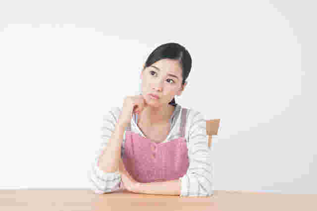 口元に手を当てて上を見上げる悩まし気な女性