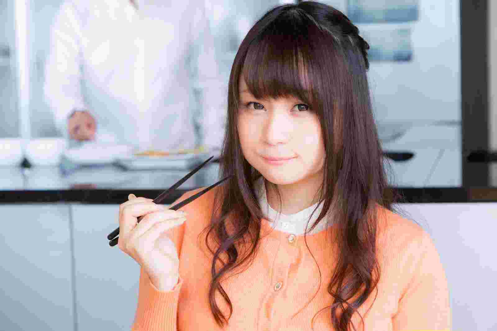 はしで食べている女性
