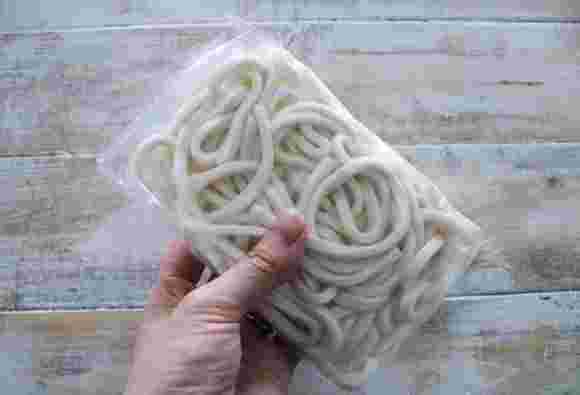 袋にパッケージされた冷凍うどん1玉を持っているところ
