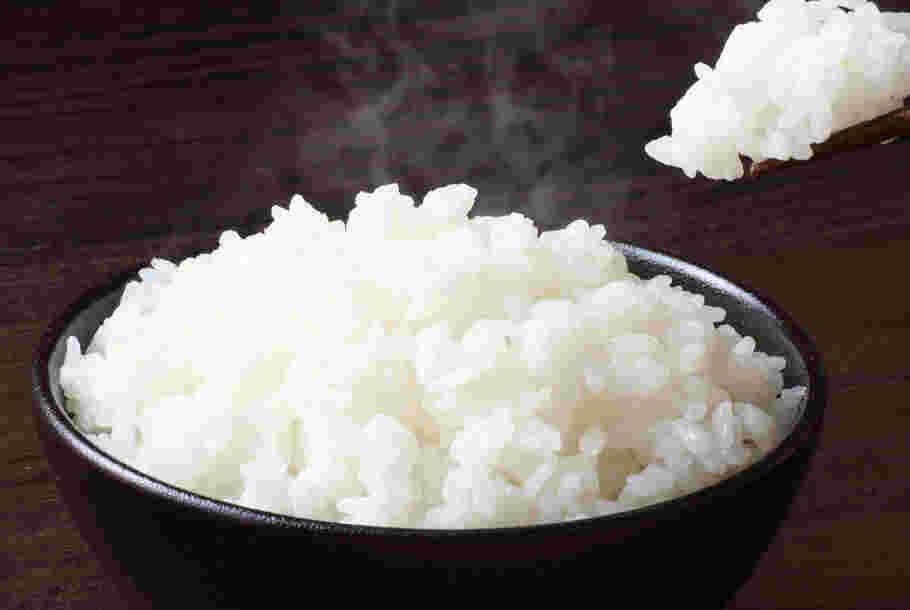黒の茶碗に入った湯気の上がるご飯