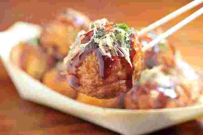 たこ焼きソースがかかったたこ焼きを持っている