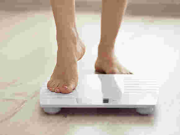 ダイエットの結果として体重計に乗って体重を計測する人