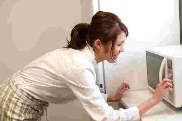 電子レンジのボタンを押す女性