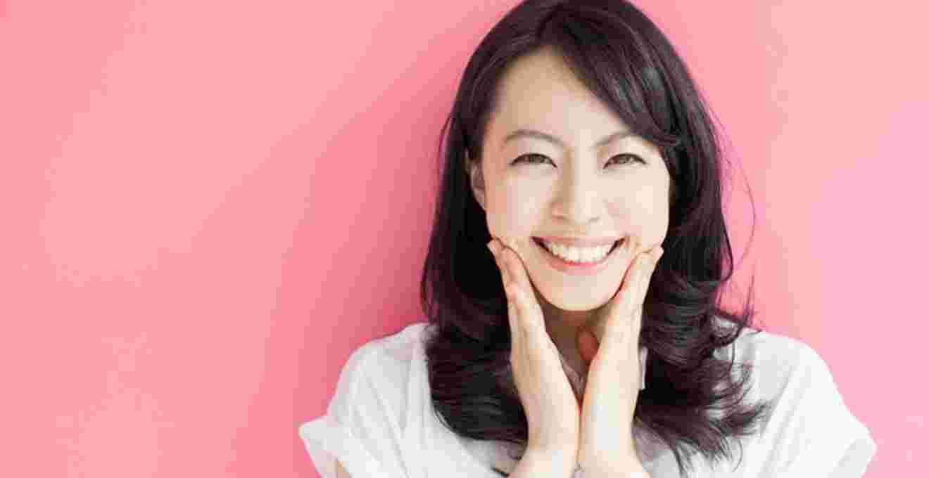 両手を頬にあてて笑顔の女性