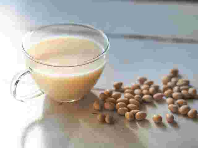 透明のカップに入ったきな粉牛乳と原料の大豆