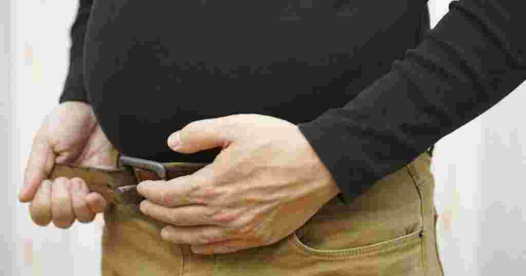 食べ過ぎてベルトがしめられない男性