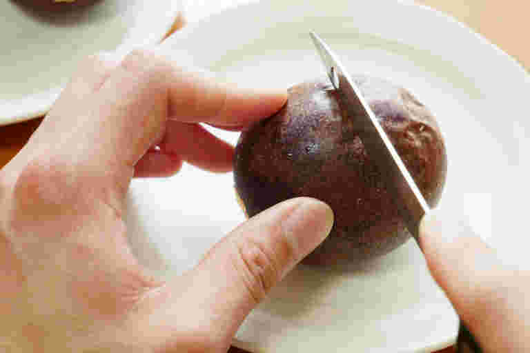 包丁で半分にパッションフルーツを切る