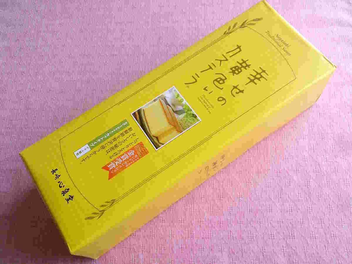 ピンクの布の上に箱に入った幸せの黄色いカステラ