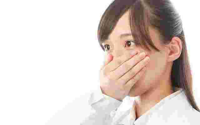 手で口をふさぐ女性
