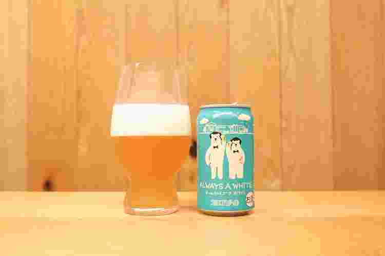 下にくぼみのあるグラスに入ったホワイトビールとその横に缶がある様子