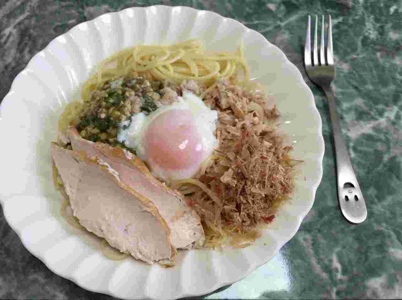 目玉焼きがのったパスタにスモークキチンが添えられている写真