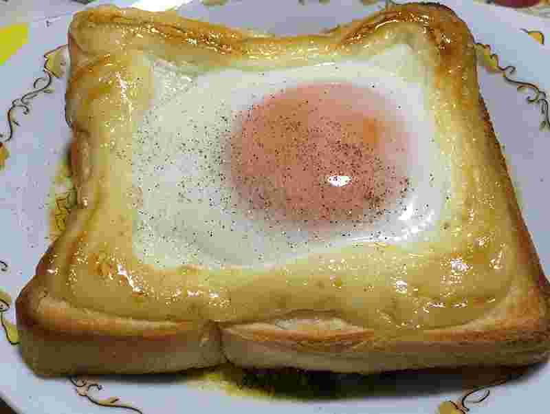 食パンの上のマヨネーズで囲われた中に半熟の目玉焼きが入っている