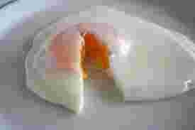 硬めに焼かれた目玉焼きを半分にカットしている様子