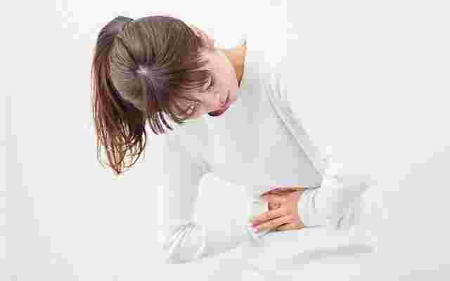 押し麦を食べ過ぎてお腹が痛くなっている女性
