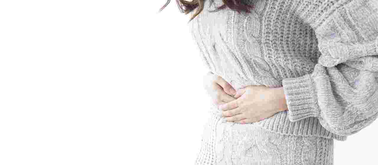 消化不良で胃もたれを起こしお腹を押さえている女性