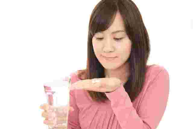 サプリメントを飲もうとする女性