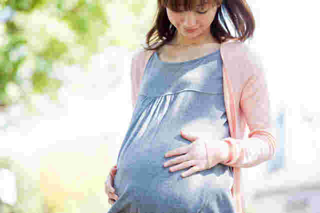 お腹に手を当てて微笑む妊婦