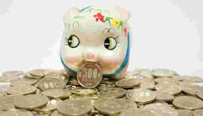 大量の500円玉の中に豚の貯金箱がある様子