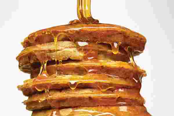 パンケーキにメープルシロップをたっぷりかけているようす