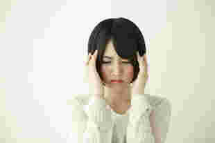 イライラしてこめかみに手を当てる女性
