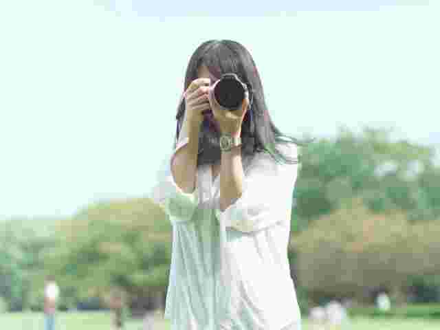 緑の中で一眼レフを持つ女性