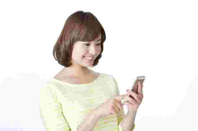 スマホを笑顔で操作する女性