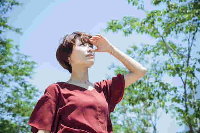 太陽の強い光を浴びて紫外線を受けている女性