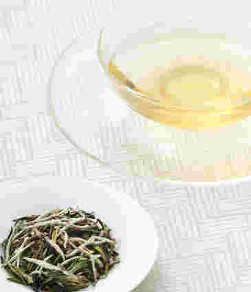 ホワイトティーの茶葉と注いだガラスのティーカップ