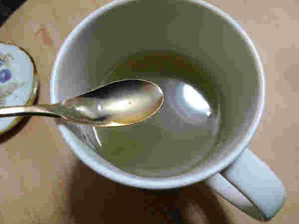 コップにいれたグリーンコーヒとスプーン