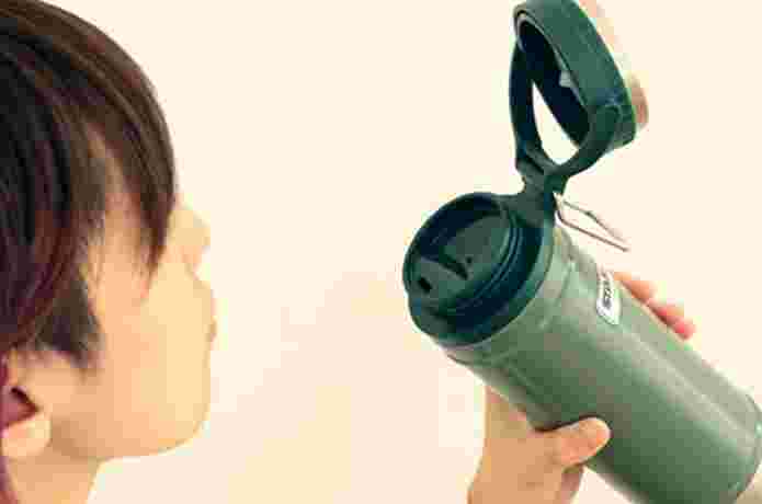 スタンレーの水筒を手に持ち飲もうとする女性
