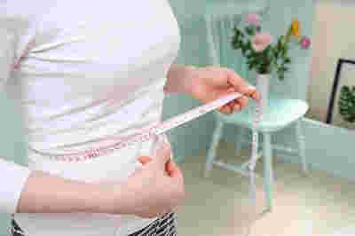 ウエストにメジャーを当ててはかる女性