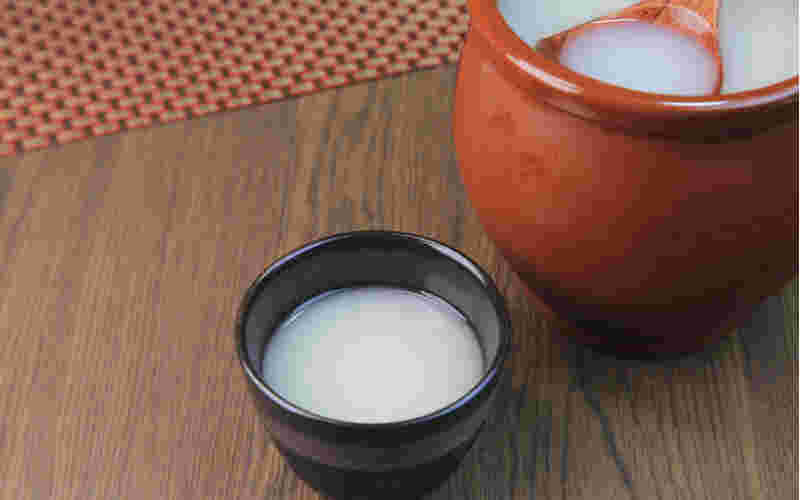 壺に入ったマッコリとおちょこに注がれたマッコリの画像