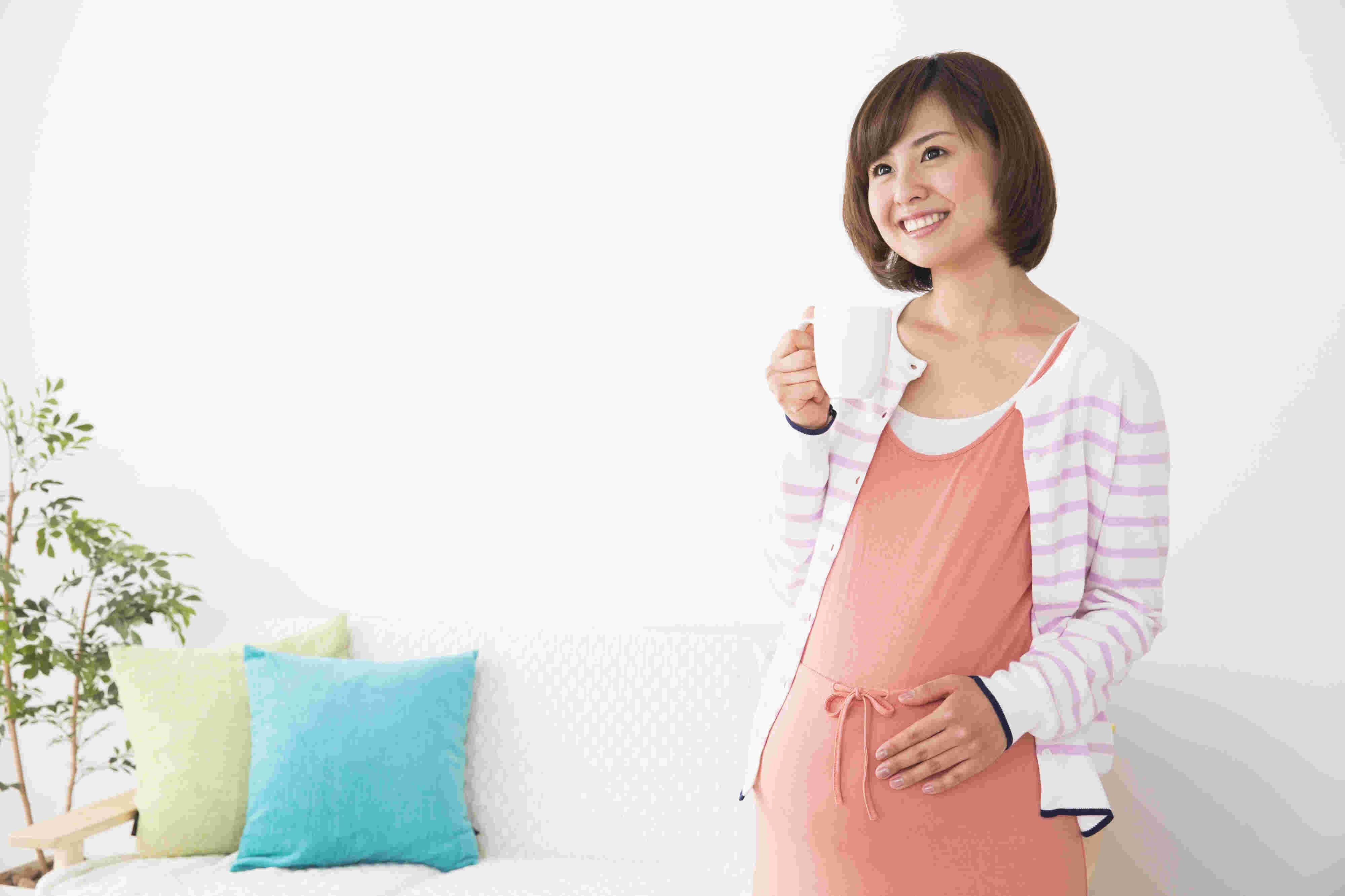 マグカップを持ち立つ妊娠中の女性