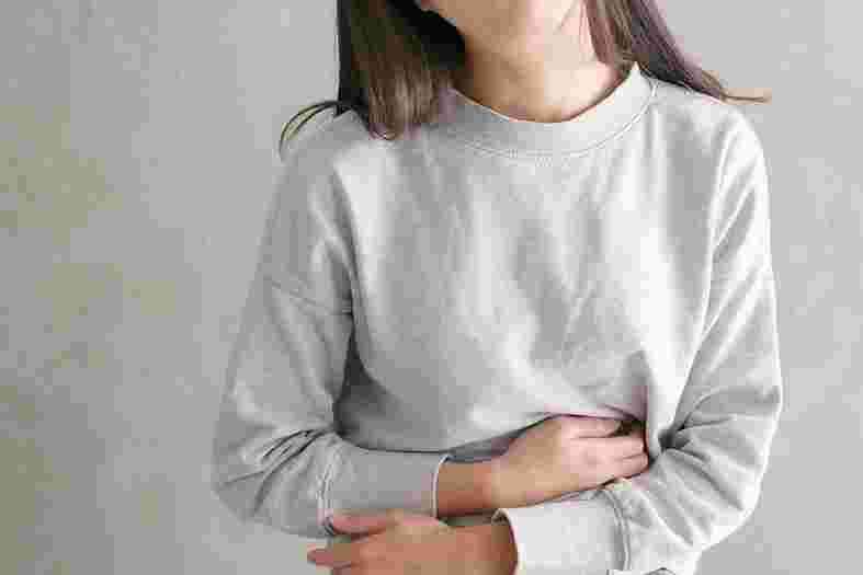 胃のあたりを押さえる女性
