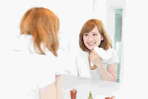 鏡を見て肌が綺麗になったのを実感している女性