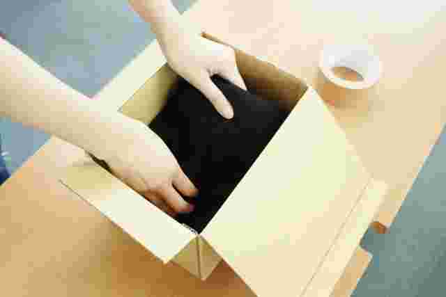 段ボールに荷物を詰める女性