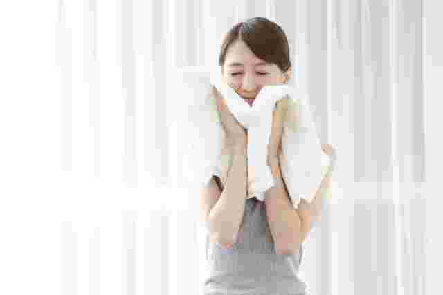 顔にタオルを当てる女性