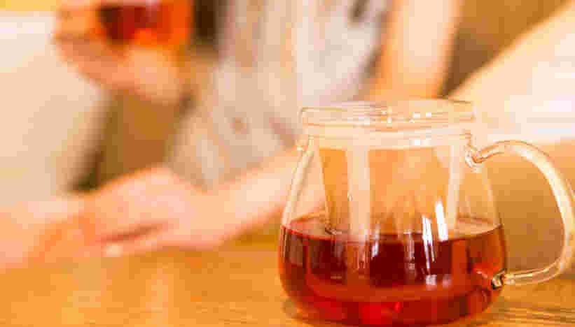 ポットからバナバ茶を注いで飲んでいる女性