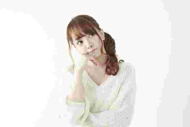 頬に手をあてて考えている女性