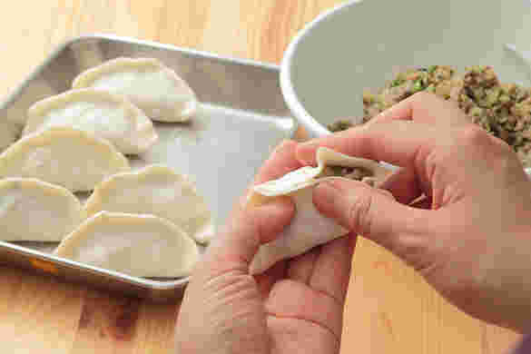 餃子の具を餃子の皮で包んでいる様子