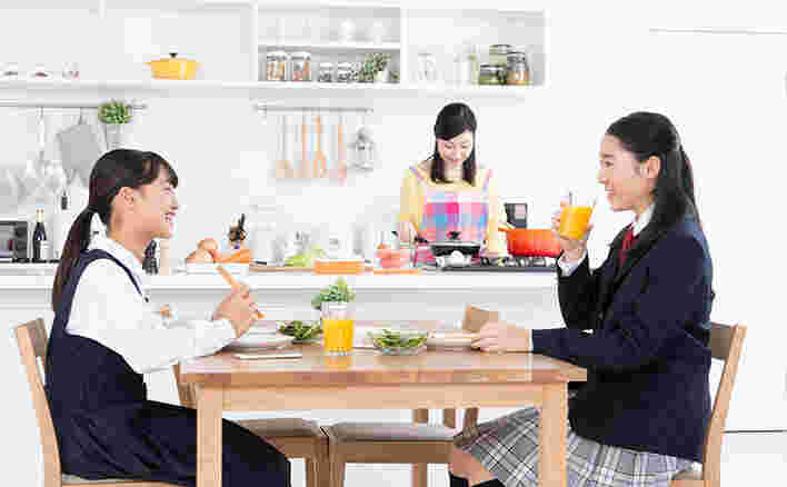 朝食を食べている姉妹と調理をしている母親