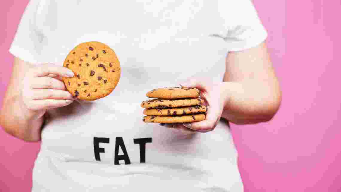 FATと書かれたTシャツを着て両手にクッキーを持っている人