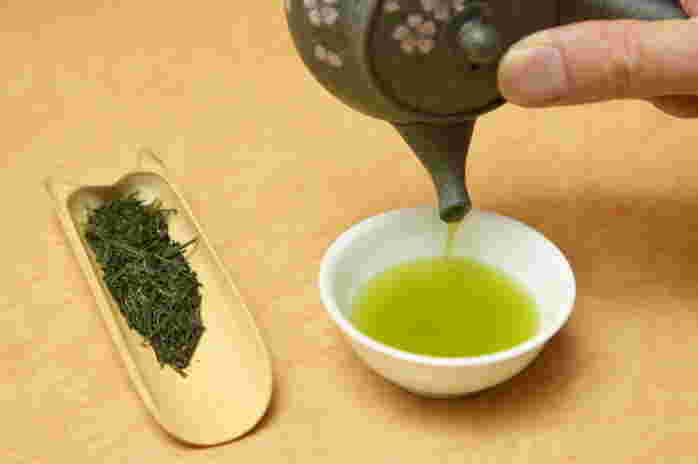 緑茶を注いでいるところ。茶碗の左には竹の茶さじに茶葉が入っている