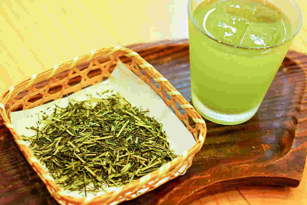 竹籠に入った茎茶と氷入りの緑茶が入ったグラスが扇型のお盆にのっている
