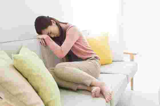 貧血で動けなくソファに座っている女性