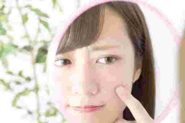 肌荒れが気になり鏡で確認している女性