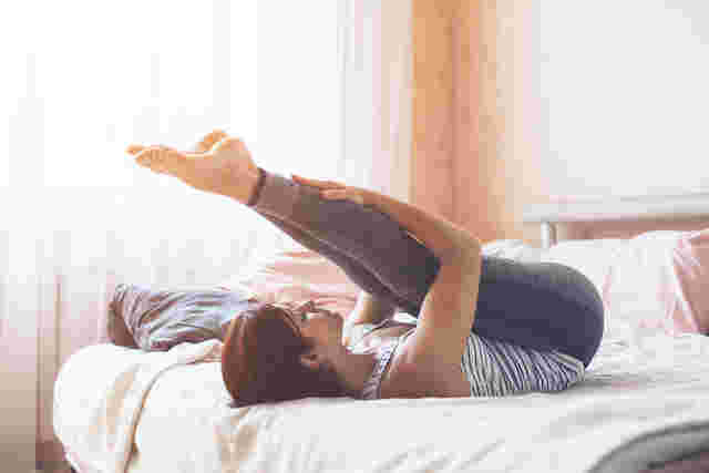 ベッドの上でストレッチする女性