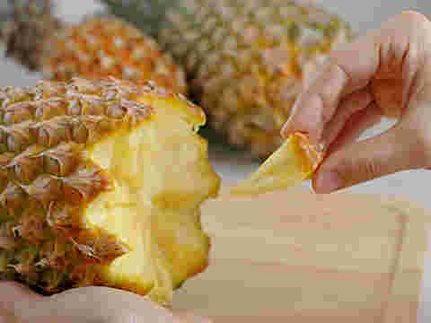 芯まで柔らかいスナックパインを手で食べている様子